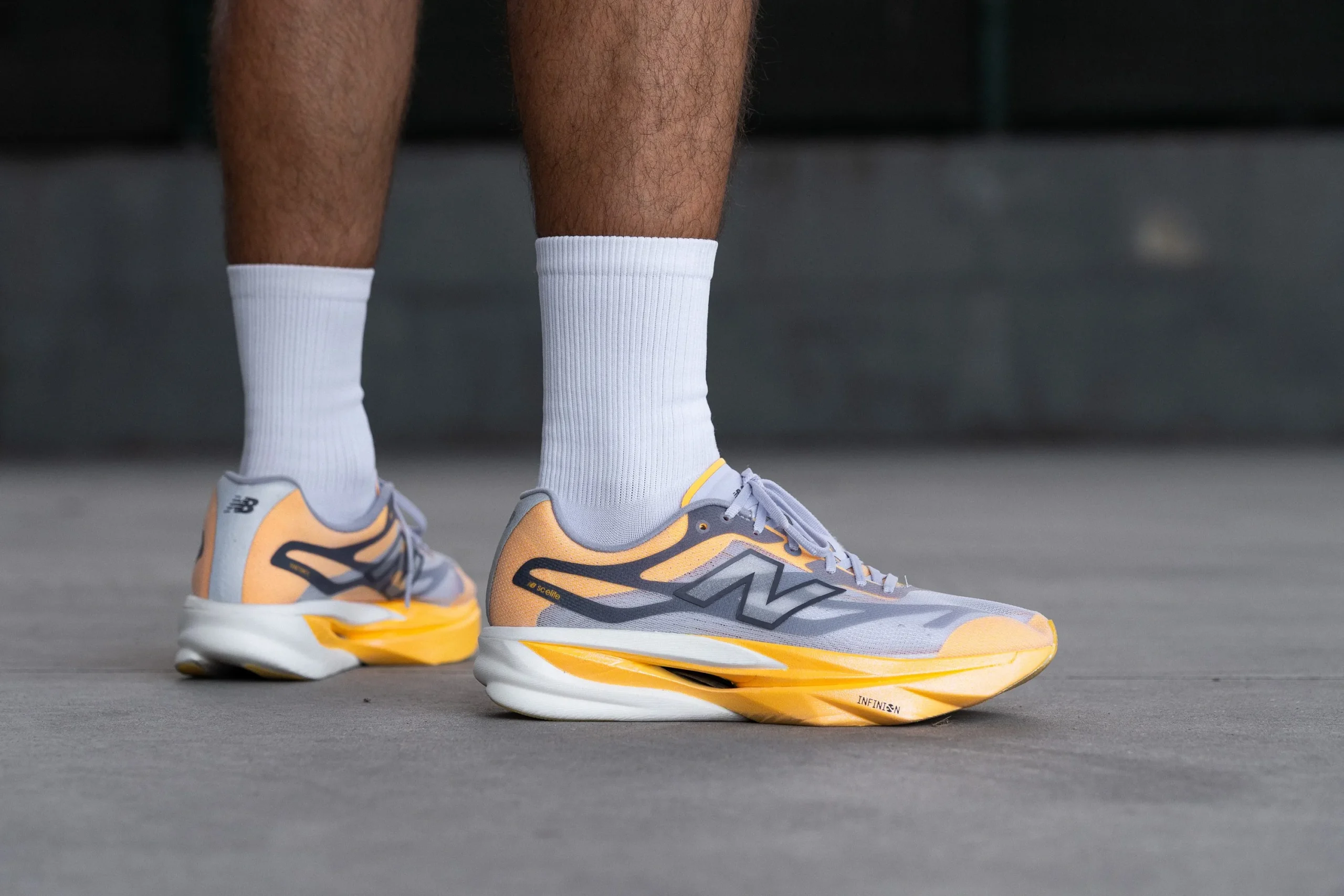 las piernas de un hombre con unas zapatillas de running New Balance grises y naranjas