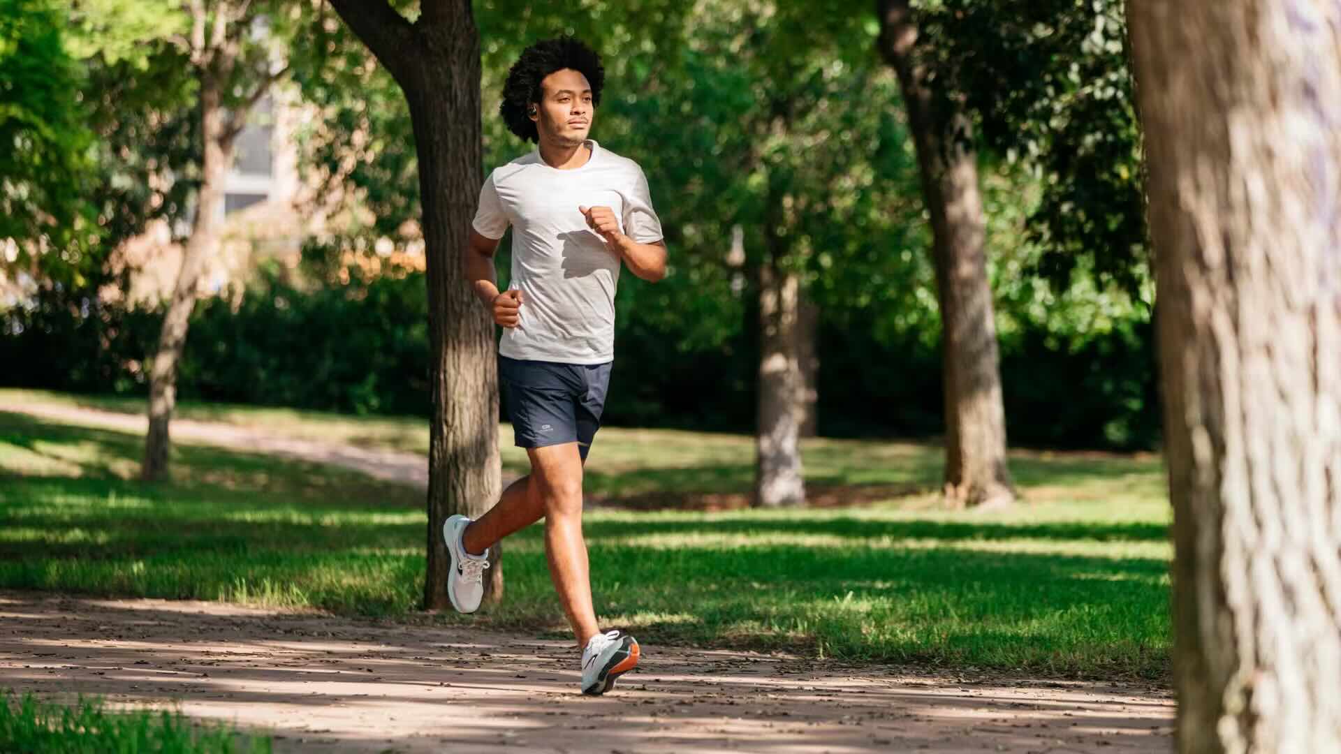 Joven corriendo en un parque con auriculares